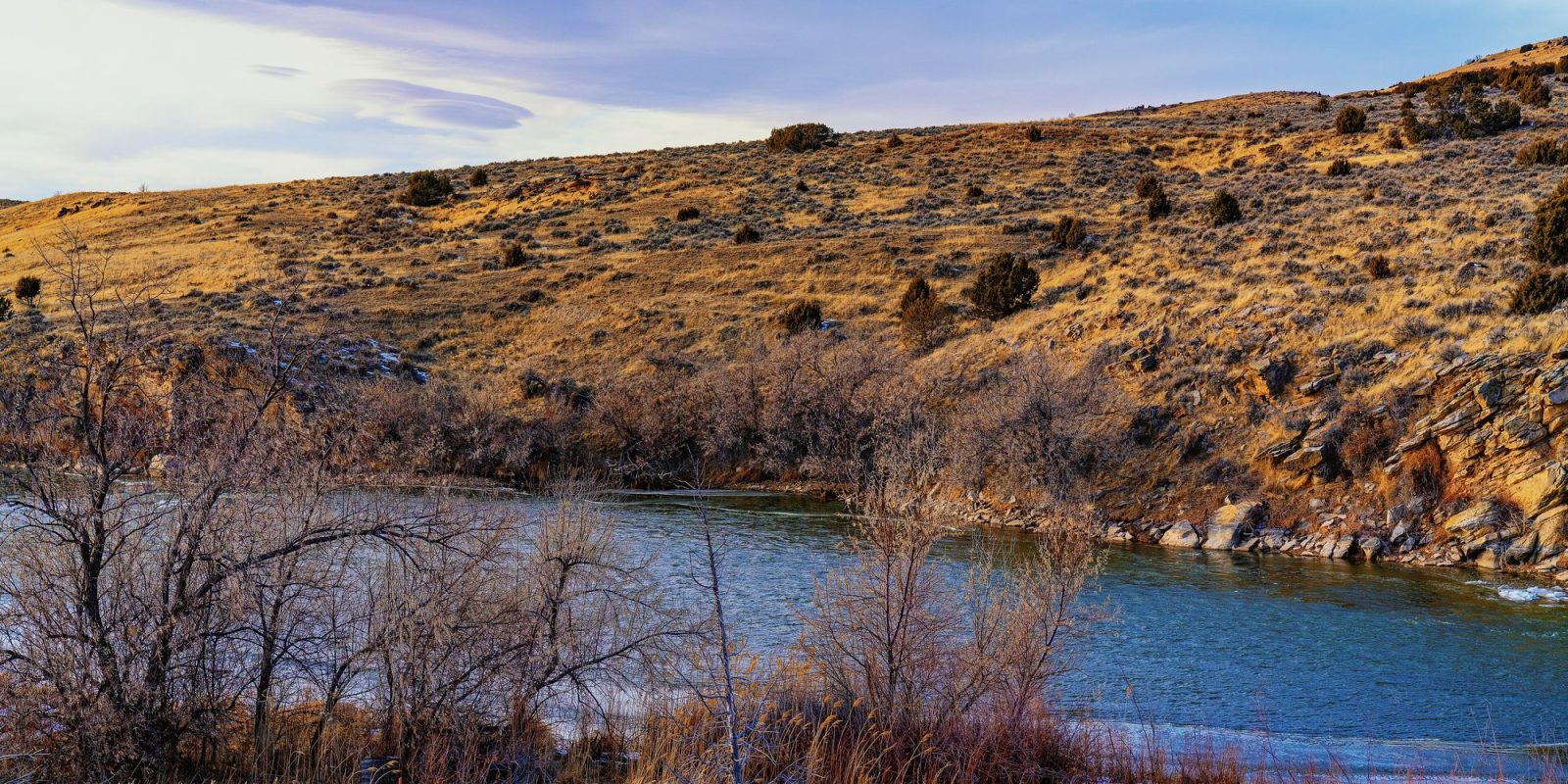 The North Platte River curving below golden, sage-dotted hills, with bare winter shrubs on the near bank