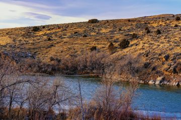 The North Platte River curving below golden, sage-dotted hills, with bare winter shrubs on the near bank