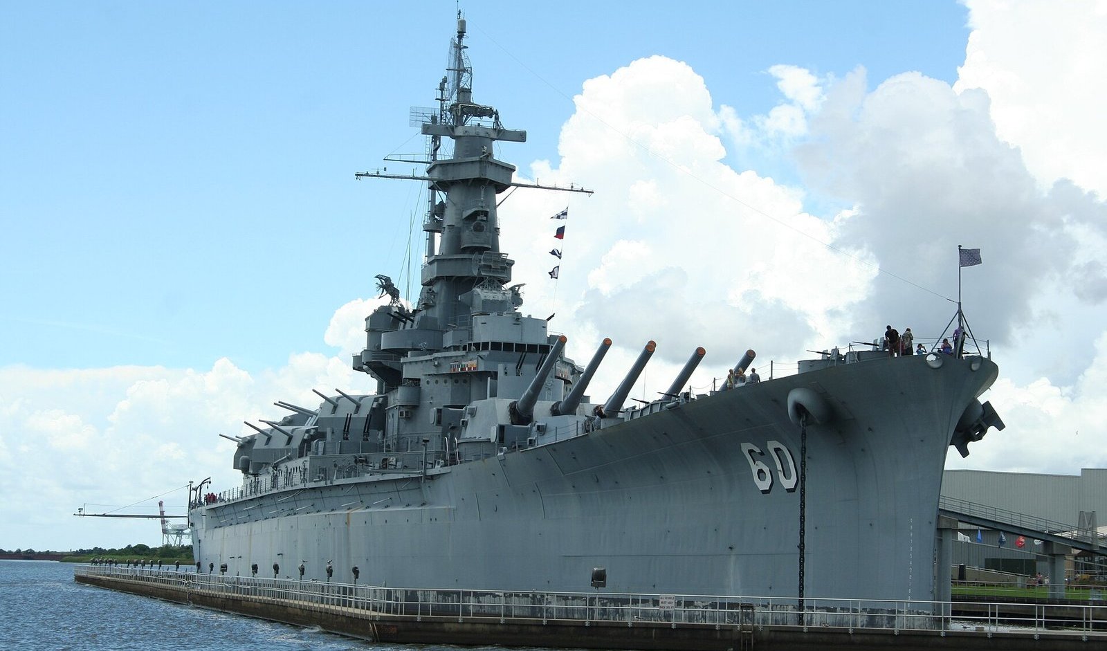 Gray battleship USS Alabama, hull number 60, berthed at Battleship Memorial Park in Mobile Bay under billowing clouds