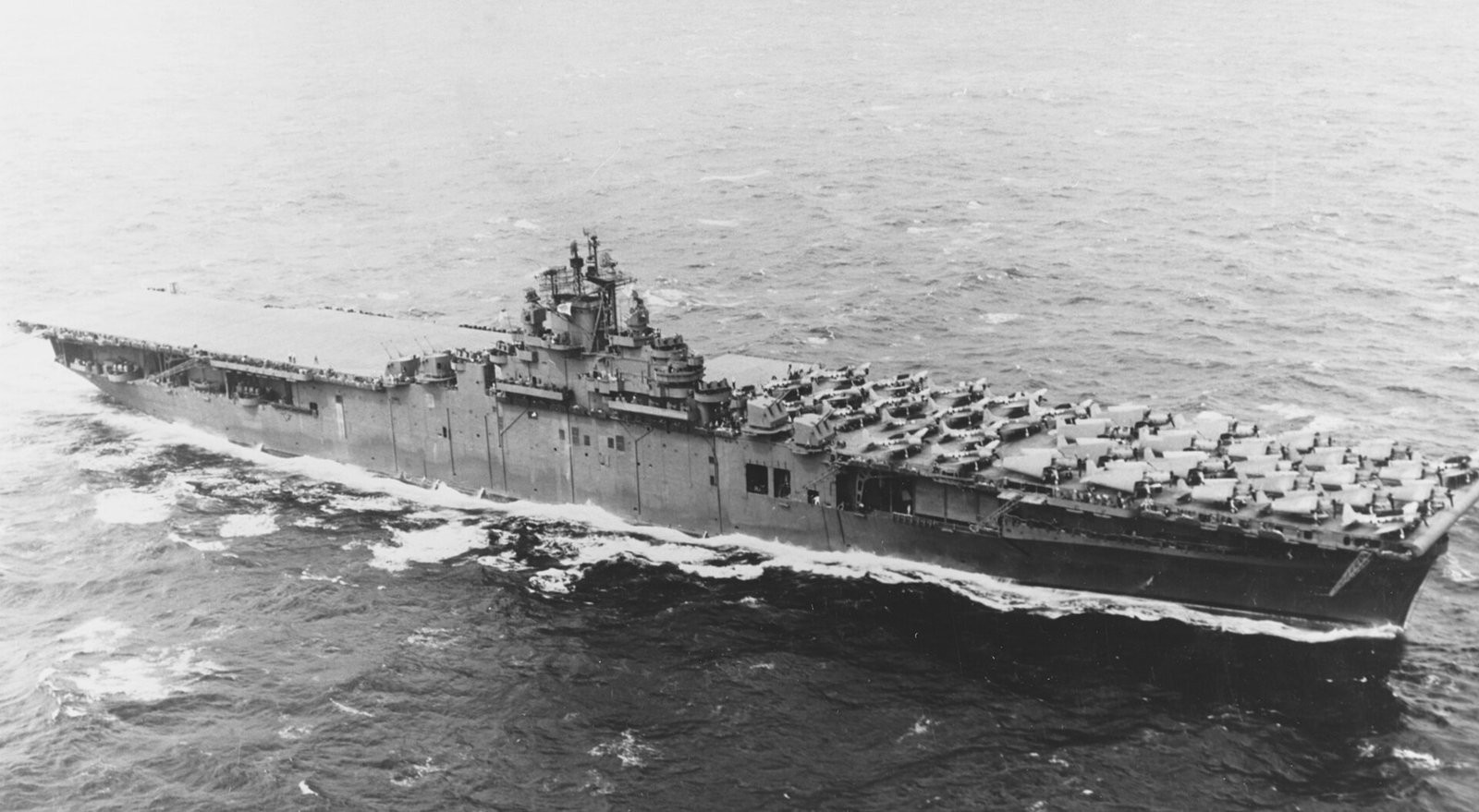 Black-and-white photo of USS Lexington at sea in 1943 with aircraft packed on her flight deck